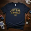 Navy t-shirt with gold text "JUST ONE MORE" featuring stacks of coins and dice, perfect for gambling enthusiasts
