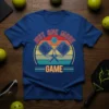 Blue t-shirt with "Just One More Game" text and graphic of crossed pickleball paddles and ball, featuring a retro sunset