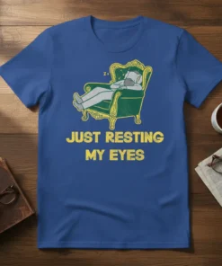 Blue t-shirt with yellow text "JUST RESTING MY EYES" and a cartoon of a person sleeping in an ornate chair