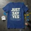 Blue t-shirt with white and yellow text "JUST SAY YES" surrounded by colorful fireworks graphic