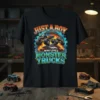 Just A Boy Who Loves Monster Trucks text with graphic of monster trucks and cars on a black t-shirt