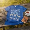 Blue t-shirt with white text "Just a Girl WHO LOVES Donkeys" and illustrations of three donkeys, flowers, and hearts