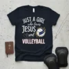 Black t-shirt with white and pink text "JUST A GIRL who loves JESUS and VOLLEYBALL" and a graphic of a