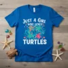 Blue t-shirt with white text "JUST A GIRL WHO LOVES TURTLES" and colorful sea turtle graphics