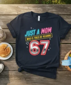 T-shirt with neon text "JUST A MOM WHO IS TIRED OF HEARING" above a large "67" graphic for a 67th