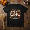 Black t-shirt with "just a thankful goose." text and cartoon geese dressed for Thanksgiving, surrounded by autumn leaves