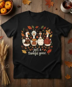 Black t-shirt with "just a thankful goose." text and cartoon geese dressed for Thanksgiving, surrounded by autumn leaves