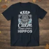 Keep Calm and Love Hippos text with a stylized hippo face and wave graphics on a navy blue t-shirt