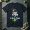 Keep Calm and Pickle On text design with pickleball graphics and palm trees on a navy t-shirt
