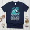 Keep Calm and Swim With Dolphins quote with dolphins jumping over ocean waves graphic on a navy t-shirt