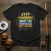 Black t-shirt with "Keep Training Until The Turns Black" text and graphic of martial arts belts, including brown, yellow, and