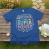 Blue t-shirt with "KINDNESS is my SUPER POWER" text in colorful, playful lettering and decorative elements