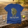 Frog with text "kiss my butt" in white outline font, cartoon style, on a blue t-shirt