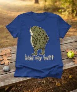 Frog with text "kiss my butt" in white outline font, cartoon style, on a blue t-shirt