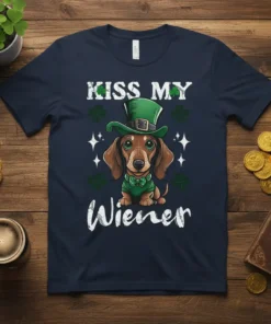 Dachshund wearing a green St. Patrick's Day hat and shirt with "Kiss My Wiener" text