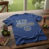 La Tia Masmas Chingona phrase in gold glitter font on a navy blue t-shirt with a lotus design below