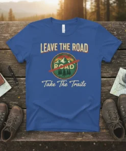 Leave The Road Take The Trails quote on a blue t-shirt with a circular mountain and trees graphic