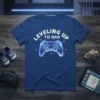 Leveling Up To Dad text with a neon geometric video game controller graphic on a navy blue t-shirt