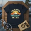 Life Is Better On A Boat t-shirt featuring a yacht sailing at sunset with vintage-inspired text and graphics