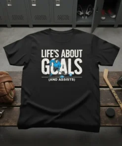 T-shirt with "Life's About Goals (And Assists)" text and graphic of a hockey player scoring a goal