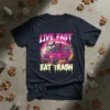 Live Fast Eat Trash t-shirt design with a sunglasses-wearing opossum driving a pink garbage truck, and a raccoon in the