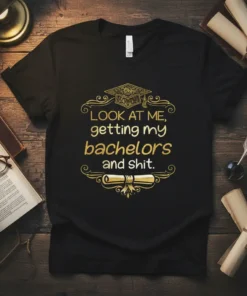Black t-shirt with gold text "LOOK AT ME, getting my bachelors and shit." and graduation cap and scroll graphics