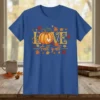 Love Fall y'all text with a pumpkin graphic surrounded by autumn leaves and acorns on a blue t-shirt