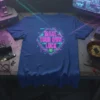 Make Your Own Luck quote in neon pink and teal lettering on a dark blue t-shirt, featuring a clover emblem