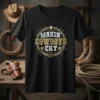 Makin' Cowboys Cry t-shirt with distressed typography and a skull graphic, set against a western-themed background