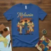 Melanin Trippin' text with three stylish black women walking with luggage at sunset graphic on a blue t-shirt