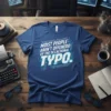 Blue t-shirt with white and light blue text reading "MOIST PEOPLE AREN'T OFFENEDD BY THE OCCACIIONAL TYPO." in a tech-inspired