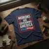 Navy blue t-shirt with "MORONS ARE GOVERNING AMERICA" text in white, framed by red stars and an American flag graphic