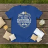 Blue t-shirt with "Most Likely To Take Cornhole Too Seriously" text, cornhole bags, and fists graphic