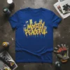 Blue t-shirt with yellow and red graffiti-style text reading "MOSTLY PEACEFUL" and urban city skyline graphic