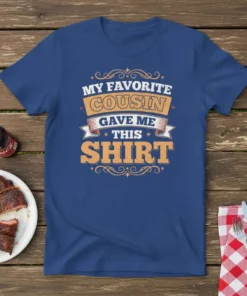 Blue t-shirt with bold orange and white text reading "MY FAVORITE COUSIN GAVE ME THIS SHIRT", featuring decorative elements
