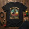 My Weiner Does Tricks t-shirt featuring a dachshund wearing a top hat riding a unicycle and juggling balls, with a