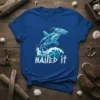 Hammerhead shark jumping over a wave with "Nailed It" text, cool geometric design, blue t-shirt