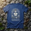 Gorilla meditating with 'Namasté' text, on a blue t-shirt, surrounded by stones and moss