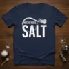 Needs More Salt text and salt shaker graphic on a navy blue t-shirt, ideal for foodies and chefs