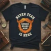 Never Fear Ginger Beard Man Is Here text with orange mustache and beard graphic on a navy t-shirt