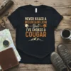 T-shirt with "Never Killed A Mountain Lion But I've Choked A Cougar" text and mountain lion graphics