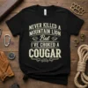 Black t-shirt with white text design that reads "Never Killed A Mountain Lion But I've Choked A Cougar" featuring lion