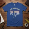 Blue t-shirt with "Never Underestimate The Power Of A Lefty" text and compass graphic for left-handed individuals