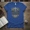 Blue t-shirt with "Not Luck Just God" text in a shield emblem featuring a Celtic cross graphic
