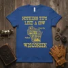 Blue t-shirt with yellow text "NOTHING TIPS LIKE A COW WISCONSIN" and a graphic map of Wisconsin filled with gears