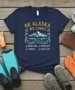 Navy t-shirt with "OK ALASKA WE COME!" text, mountains, and whale tail graphic, listing swim fins, towels, swim suit, and