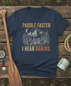 Paddle Faster I Hear Banjos text with a canoe, mountains, and trees graphic on a navy t-shirt