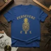 Gold steampunk pineapple graphic with "PERSEVERE ERE" text on a royal blue t-shirt