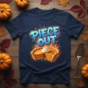 Piece Out text graphic with a slice of pumpkin pie topped with whipped cream on a navy t-shirt