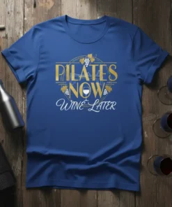 Pilates Now Wine Later quote on a royal blue t-shirt with gold and white lettering, featuring grapevines and a wine
